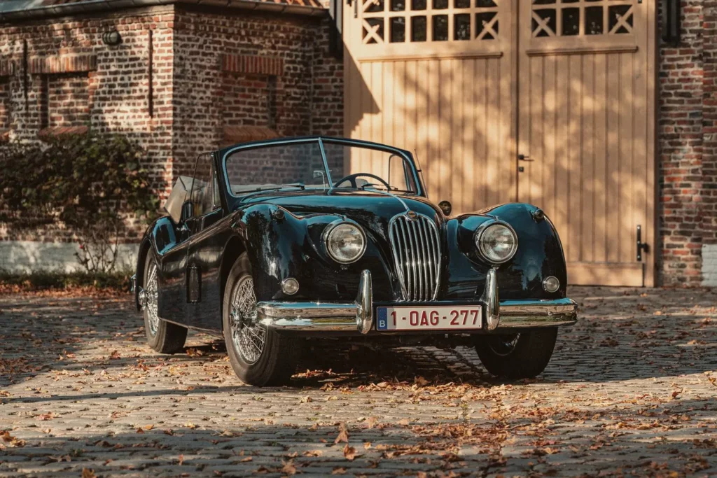 Jaguar XK140 van voren gezien voor de poort van het atelier op Diepenbroekhof