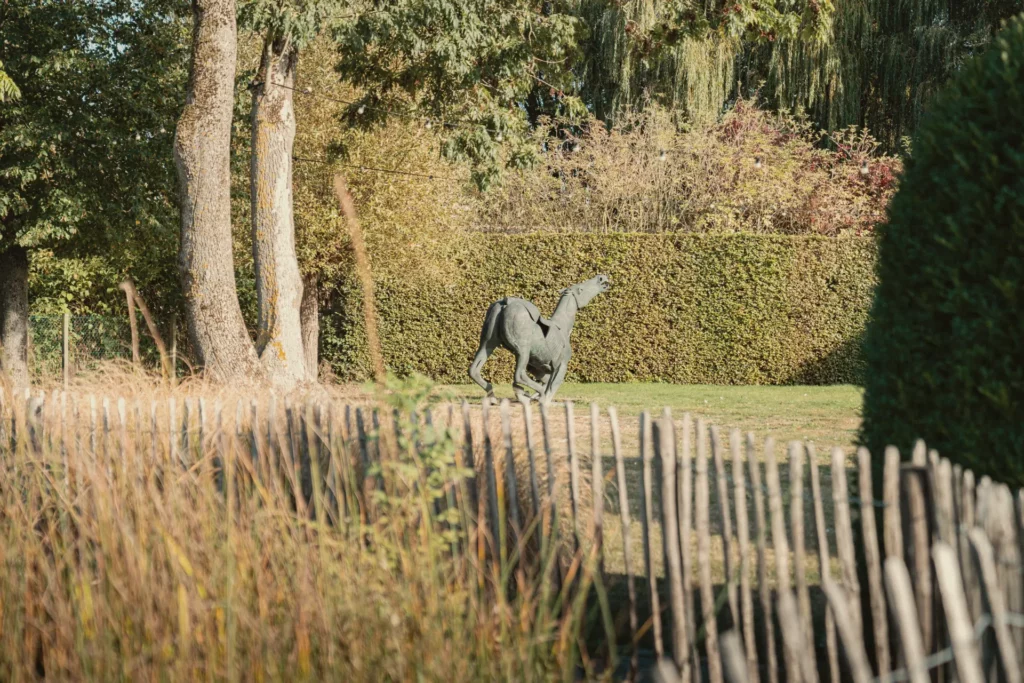 Bronzen paard achter het kastanjehouten hek in de tuin van Diepenbroekhof
